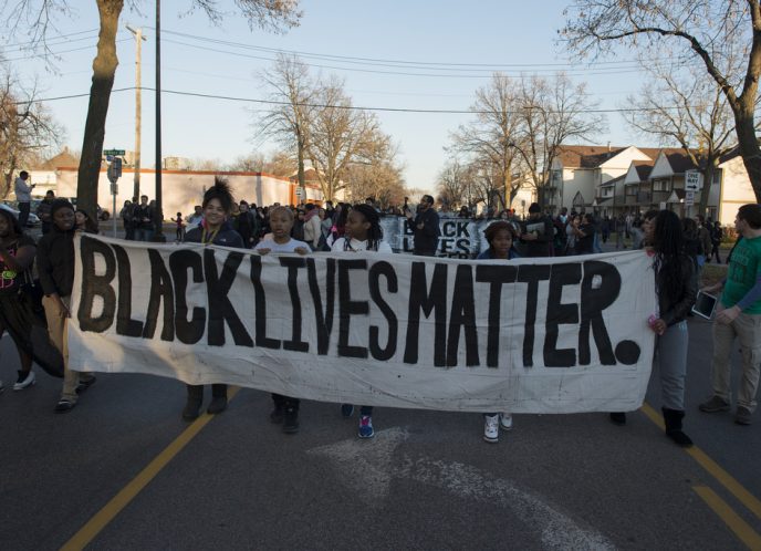 Black Lives Matter activists carry a large banner displaying "Black Lives Matter." during a protest.