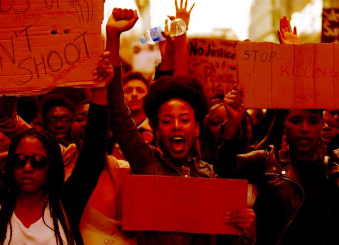 A Black woman raises her fist, surrounded by other Black protestors.